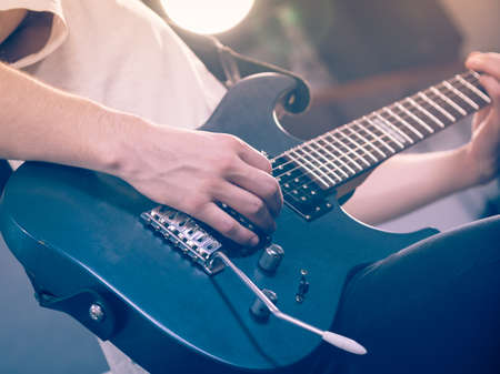 Close up of man playing on electric guitar during gig or at music studio. Musical instruments, passion and hobby concept.の写真素材