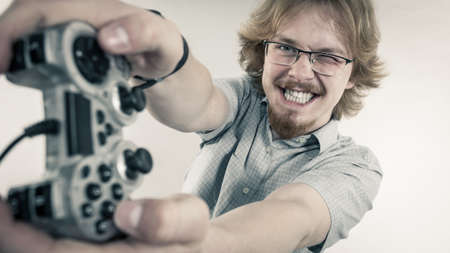 Nerd geek young adult man playing on the video console holding game pad. Gaming gamers concept.