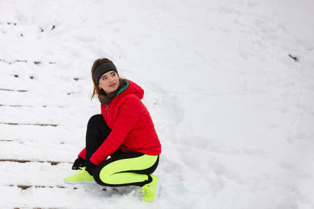 Winter sports fashion concept. Woman tying sport fitness shoes in snow, footwear for workout outside