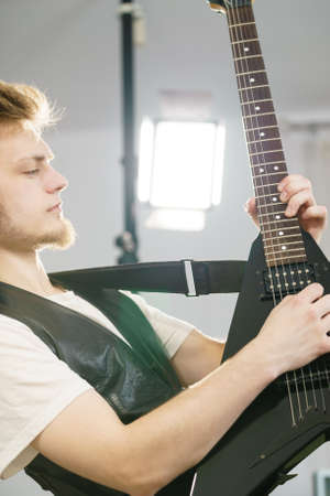 Teen hardcore man wearing metal outfit playing on electric guitar heavy rock music.