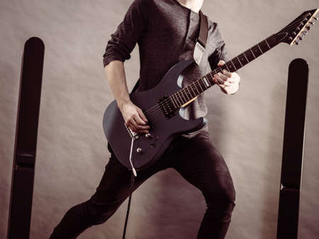 Unrecognizable male person with electric guitar. Close up, part body guy is holding instrument and playing. Hobby, music conceptの写真素材