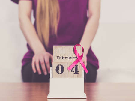 Woman and calendar, it is 4 february world breast cancer day, date with pink awareness ribbon. Healthcare and medicine concept.の写真素材