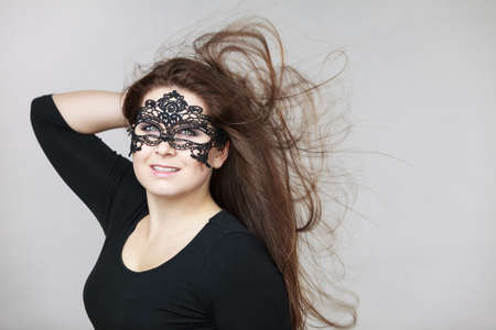 Happy pretty mysterious woman wearing black eye lace mask having long brown hair.の写真素材