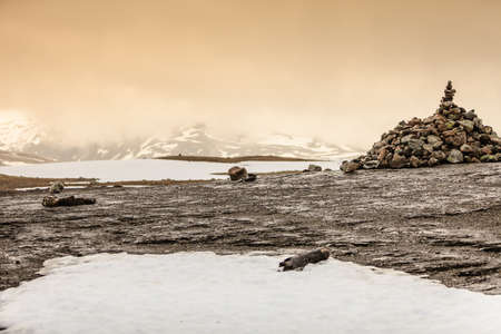 Tourism vacation and travel. Stone stack in foreground and snowcapped mountain hills covered with...