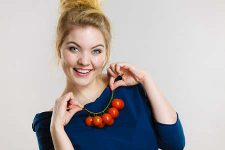 Organic vegetables and food concept. Happy positive smiling woman holding fresh cherry tomatoesの写真素材