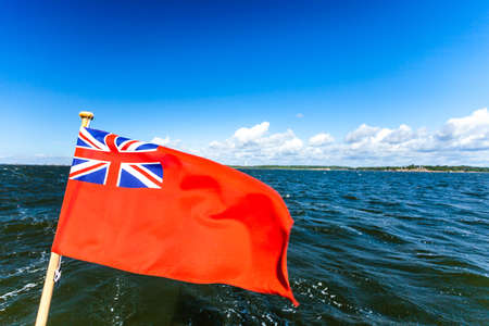 The uk red ensign the british maritime flag flown from yacht sail boat, blue sky and baltic sea. Summer and travel voyageの写真素材