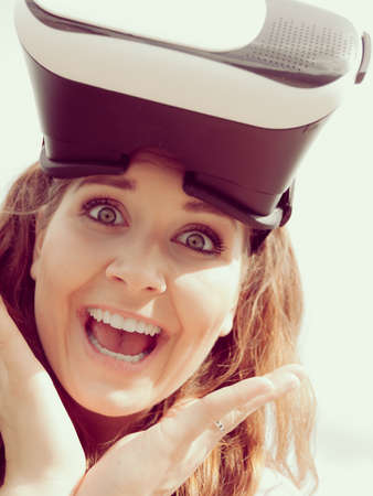 Young woman testing VR eyeglasses outside. Female wearing virtual reality headset during summer...