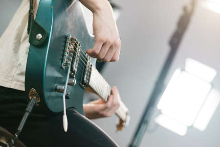 Close up of man playing on electric guitar during gig or at music studio. Musical instruments, passion and hobby concept.の写真素材