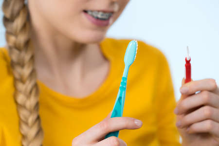 Dentist and orthodontist concept. Young woman smiling cleaning and brushing teeth with braces using...