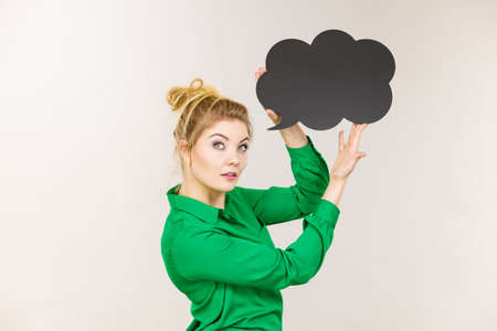 Student looking business woman wearing green shirt holding black thinking bubble on grey background.の写真素材