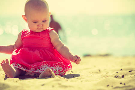 Small child sitting, playing and having fun on the beach near the sea.の写真素材