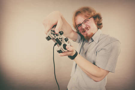 Nerd geek young adult man playing on the video console holding game pad. Gaming gamers concept.