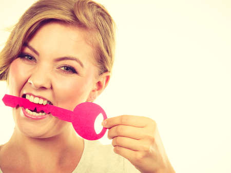 Language barrier concept. Teenage blonde girl with braid hair biting big pink keyの写真素材