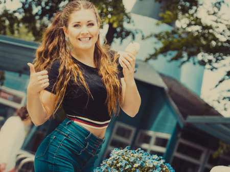 Happy funny young woman with long brown hair eating ice cream having fun.の写真素材