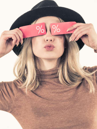 Woman in hat showing tag with shopping sale percentage sign enjoying cheap clothing. Female wearing...