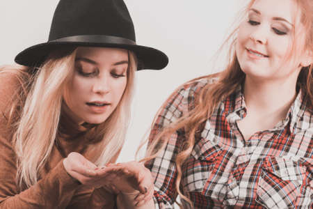 Two fashionable female friends having fun time together showing their beautiful painted nails.の写真素材