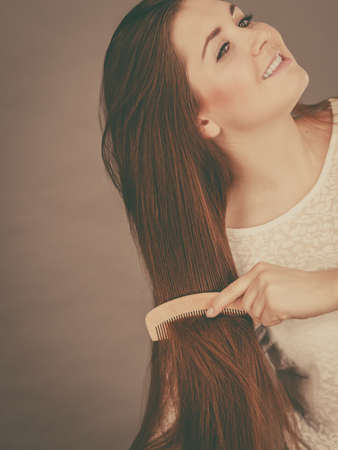 Haircare and morning hairstyling concept. Happy woman brushing her long dark brown hairの写真素材