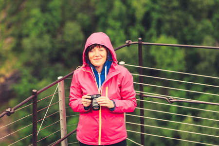 Tourism vacation and travel. Female tourist taking photo with camera in rocky summer mountains, Norway Scandinavia.の写真素材
