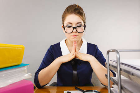 Woman sitting working at desk full off documents in binders thinking about something.の写真素材