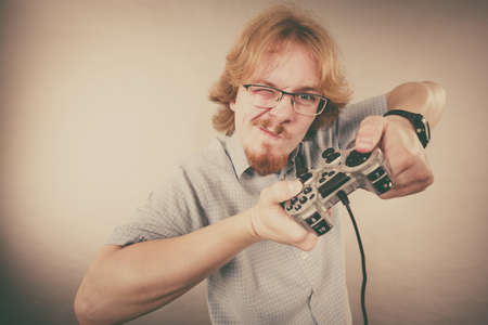 Nerd geek young adult man playing on the video console holding game pad. Gaming gamers concept.