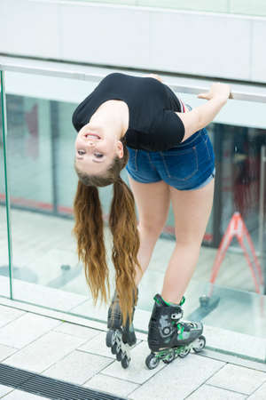 Happy joyful young woman wearing roller skates riding in town. Female being sporty having fun during summer time.の写真素材