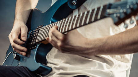 Male hands with electric guitar. Close up, part body adult person is holding instrument and playing. Hobby, music conceptの写真素材