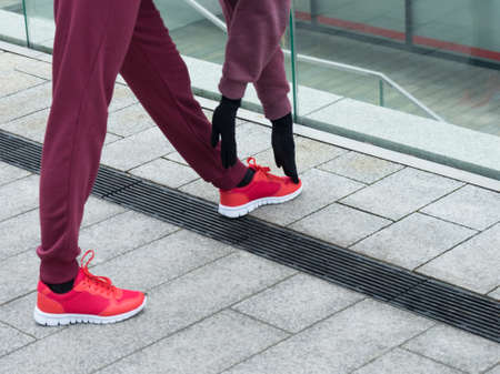 Sport and recreation. Fit slim sporty teen girl stretching warming up outdoor on city street. Woman exercising on fresh air.の写真素材