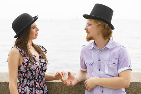 Vintage funny retro couple, man and woman enjoying their romantic date outside wearing fedora hats by seasideの写真素材