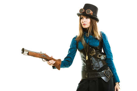 Young steampunk islolated girl on white wearing fancy hat. Fantasy old fashion with stylish topper goggle and gun aiming.の写真素材