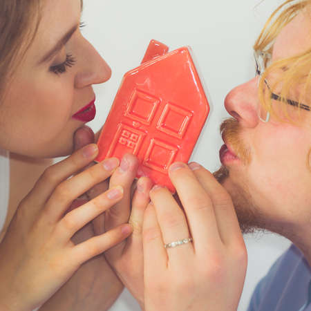 Couple being happy about new apartament. Man and woman kissing house model. New home buying, real estate concept.の写真素材
