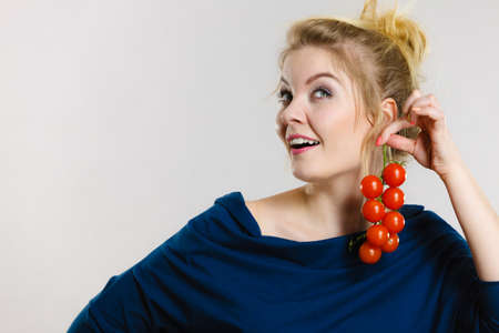 Organic vegetables and food concept. Happy positive smiling woman holding fresh cherry tomatoesの写真素材
