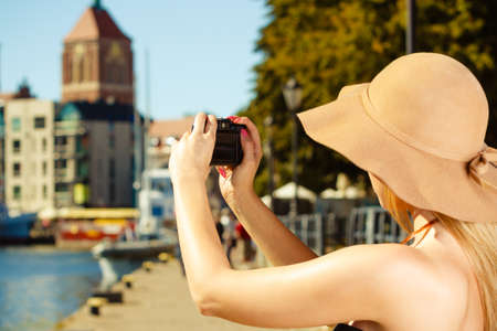 Tourism, artistic, elegant fashion. Woman in elegant outfit and sun hat taking pictures.