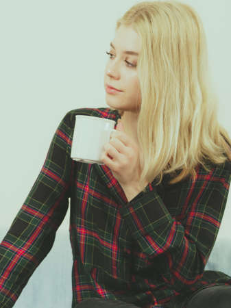 Young adult or teenage woman enjoying her leisure time drinking coffee or tea from mug.の写真素材