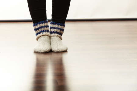 Winter accessories concept. Woman feet standing on floor, closeup of female warm woolen socks.の写真素材