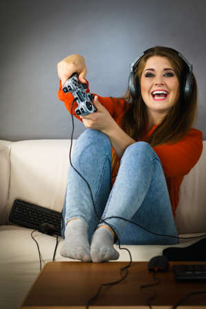 Nerd geek young adult women playing on the video console holding game pad sitting on sofa. Gaming...