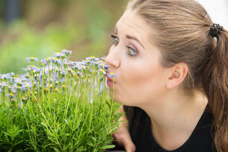 Close up of happy woman smelling wild flowers. Female being with nature