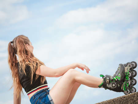 Happy joyful young woman wearing roller skates relaxing after long ride. Female being sporty having fun during summer time near sea.の写真素材