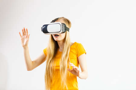 Young woman wearing virtual reality goggles headset, vr box, stretching arms. Connection,...