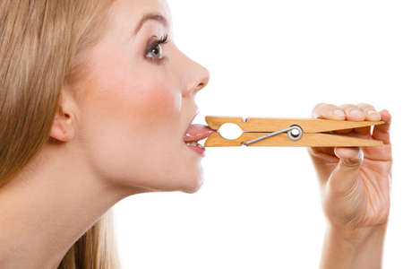 Language barrier, rumors, problems with expressing concept. Blonde woman having tongue in clothespin