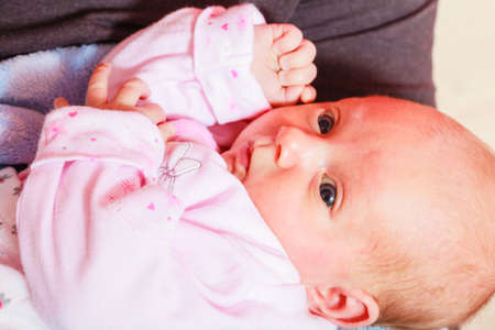Little newborn baby in pyjamas lying on back. Face expression. Family, parenthood, childhood concept.の写真素材