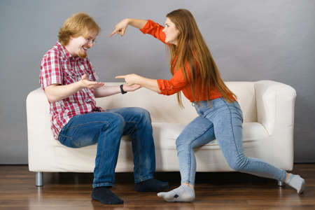 Man and woman having horrible fight while sitting on sofa. Friendship, couple breakup difficulties and problems concept.の写真素材