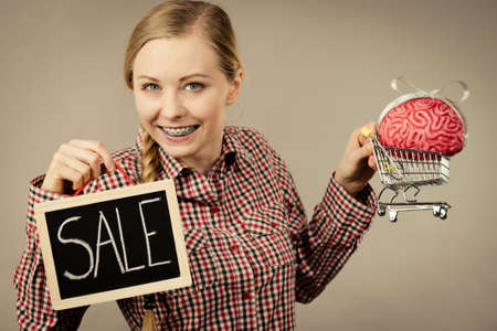 Happy woman holding shopping cart with brain inside and sale sign. Clever, responsible buying...