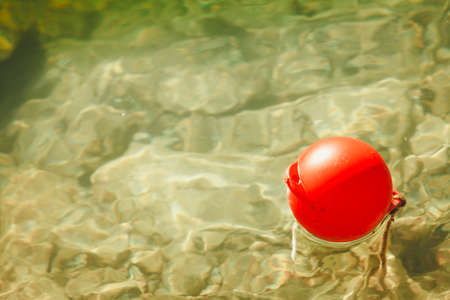 One lonely red ball buoy on water captured high angle view outdoor.