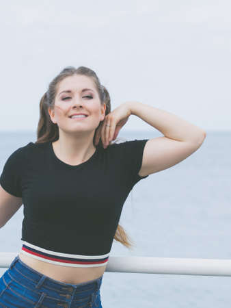 Happy teen woman enjoying her leisure time. Female having long brown hair posing with sky in backgroundの写真素材