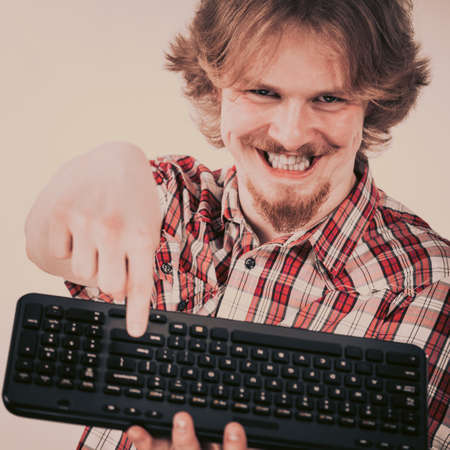 Nerd geek young adult man playing video games holding computer keyboard. Being addicted to gaming concept.の写真素材