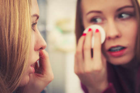 Skin complexion care concept. Young woman using cotton pad to remove make up or dirt from face.の写真素材