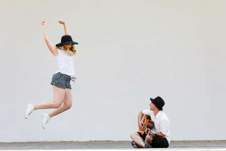 Relationship goals concept. Couple on romantic date. Man playing guitar and woman having fun jumpingの写真素材