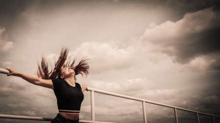 Happy joyful woman spending her free time outside enjoying beautiful summertime weather having beautiful tousled with wind brown hair.の写真素材