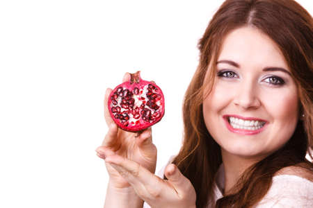 Woman cheerful brunette girl holding pomegranate fruits in hands, isolated on white. Healthy eating, cancer prevention, immune support.の写真素材