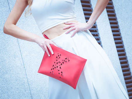 Unrecognizable fashionable woman wearing high fashion fashionable outfit showing red purse bagの写真素材